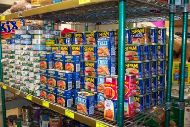 Food pantry shelf with lots of Spam and other canned meats.